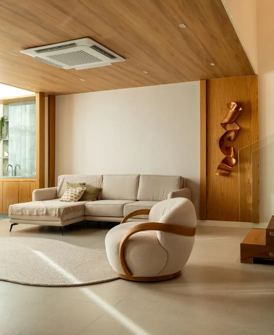 Vista ampla do living com escultura em cobre e mobiliário em tons neutros