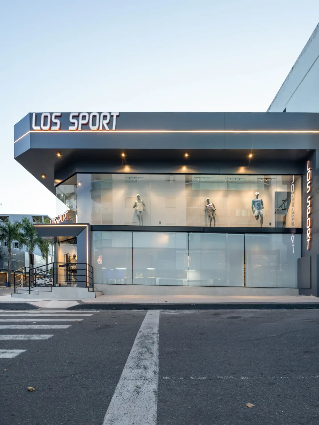 Fachada lateral da loja Los Sport com letreiro iluminado e vitrines envidraçadas