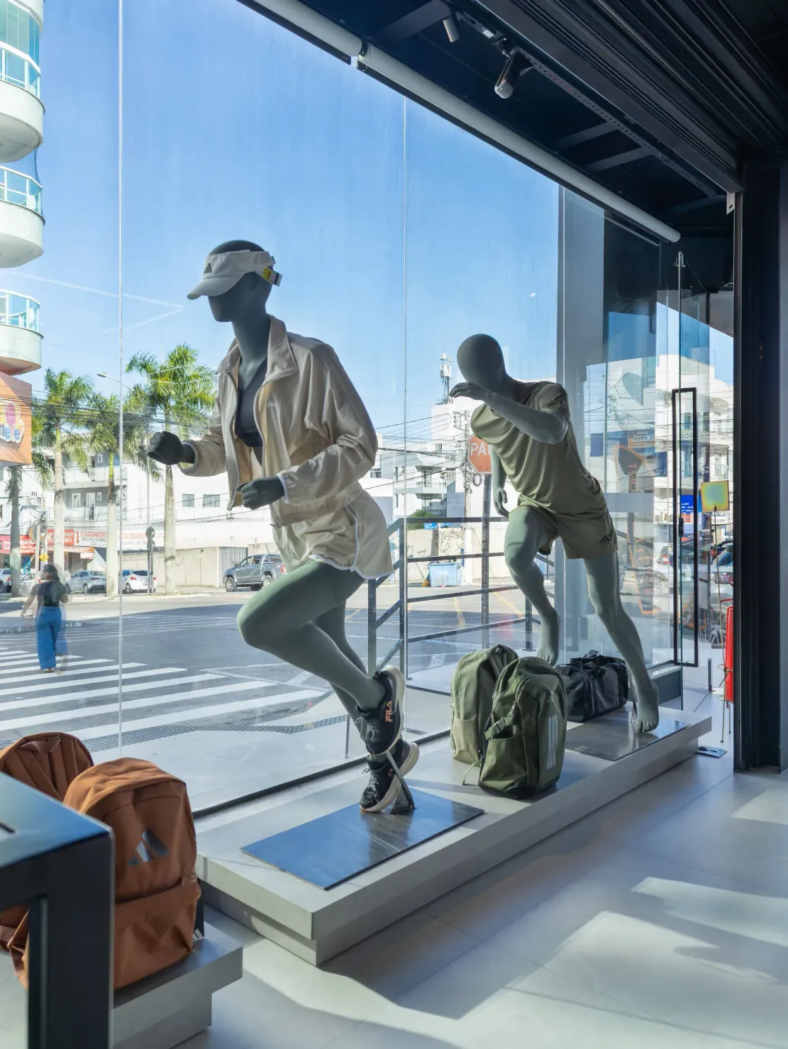 Vitrine interna da loja Los Sport com manequins em movimento e luz natural entrando pelo vidro